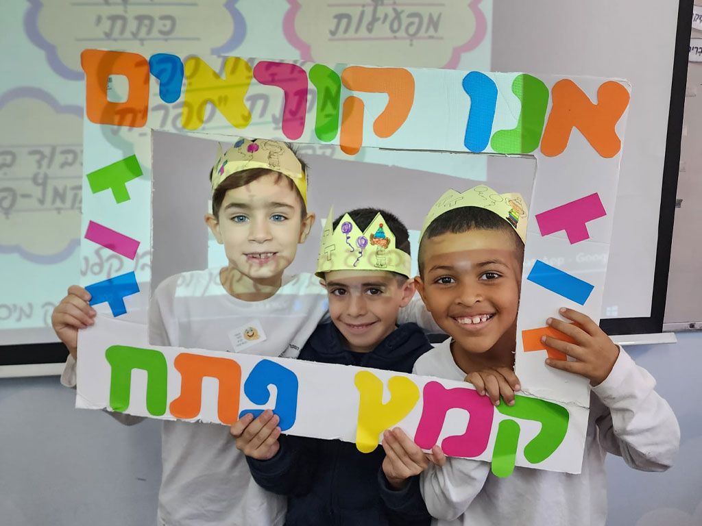3 children holding a sign we read Kametz Tamach